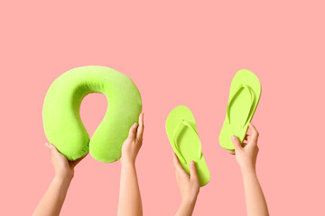 Many hands with travel cushion and flip flops on pink background