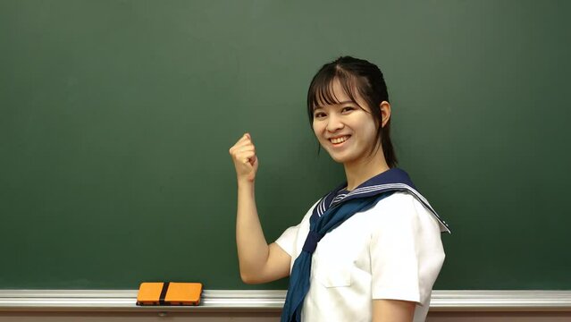 黒板でガッツポーズをする女子高生