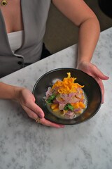 Caucasian Woman's Hands Holding a Delicious Ceviche Plate on White Table Background