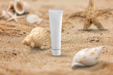 White tube bottle of sunscreen on golden sandy beach