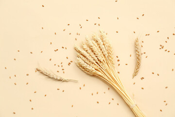 Bundle of wheat ears and grains on beige background