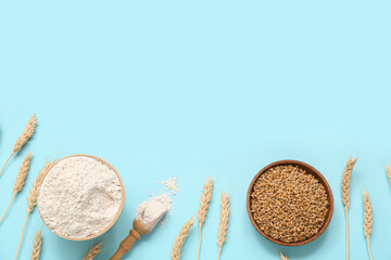 Bowls with wheat flour, grains and spikelets on blue background