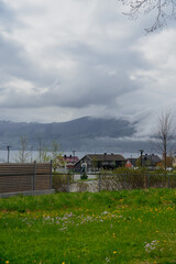 Fototapeta na wymiar View of small town in Norway against backdrop of mountain in cloudy weather.