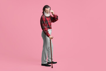 Senior man with walking cane on pink background