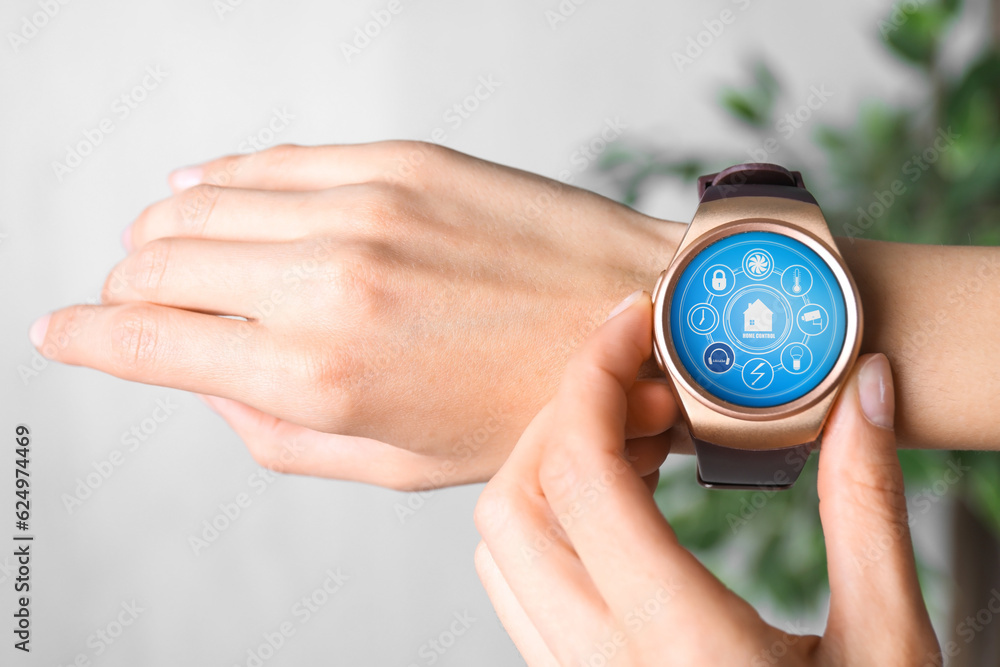 Poster woman setting smart home control system via smartwatch indoors, closeup. app interface with icons on