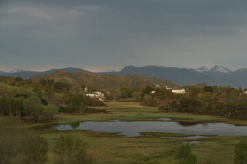 View of village in Norway surrounded by mountains at sunset after rain