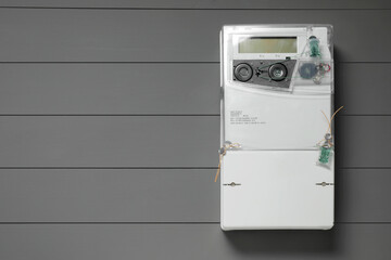 Electricity meter on grey wooden wall, space for text