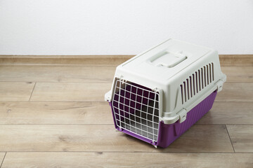 Violet pet carrier on floor near white wall. Space for text