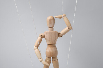 One wooden puppet with strings on light grey background