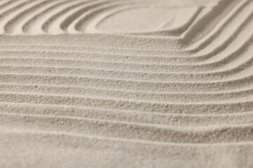 Fototapeta na wymiar Beautiful lines drawn on sand, closeup. Zen garden