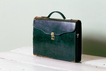 A dark leather vintage briefcase on a white table