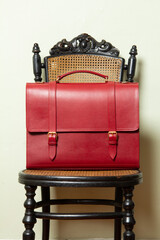 Red leather messenger bag on a black chair