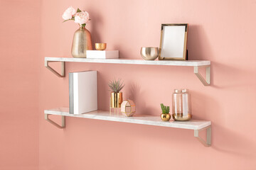 Fototapeta na wymiar white shelves hanging to a pink wall with minimal gold color home decor accessories