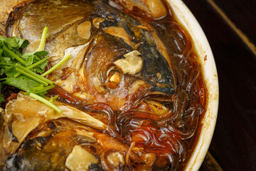 Obraz na płótnie Canvas Stewed fish head with vermicelli, a special dish of Northeast China on a wooden background