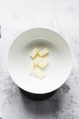 pieces of butter in a white bowl, organic butter in a white mixing bowl