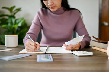 A serious Asian woman checking her electric bills and planning her household expenses.