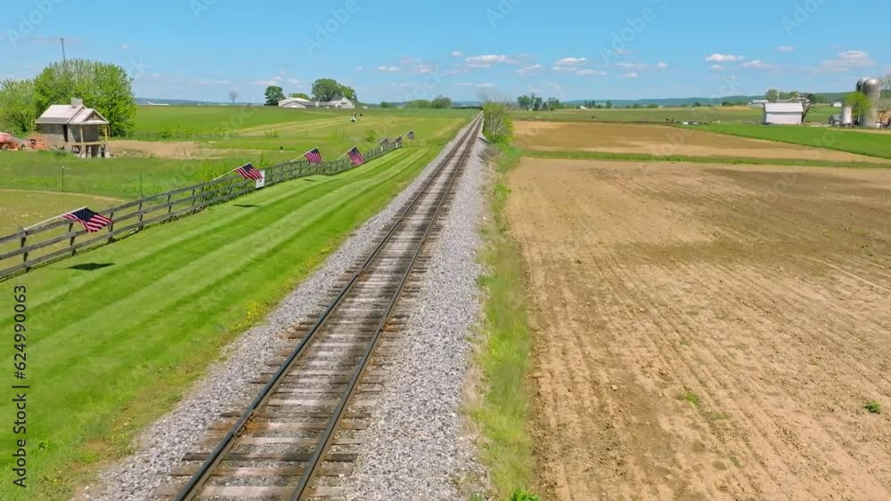 Aufkleber a drone static view of a single empty rail road track that goes thru green farmlands with a fence wi