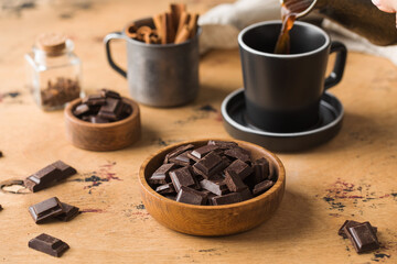 Cubes of dark artisan chocolate in a wooden bowl. Bitter chocolate