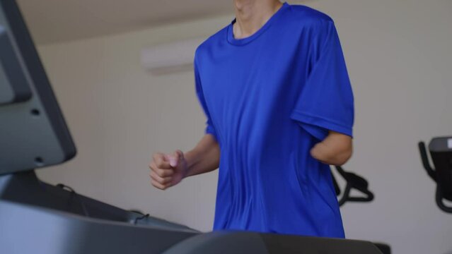 Asian young amputee without arm run on treadmill machine in fitness.