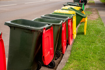 Australian garbage wheelie bins with colourful lids for general and recycling household waste on the street kerbside for council rubbish collection. - obrazy, fototapety, plakaty