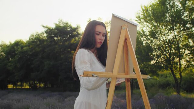 Amidst the allure of a colorful lavender field, a talented artist, a caucasian woman, lets her brush dance on the canvas, crafting a stunning portrait that embodies the beauty of nature.