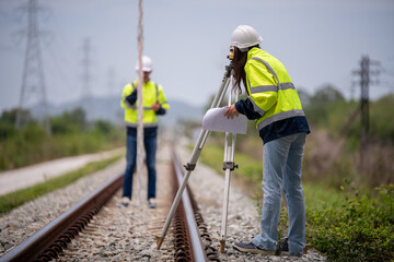 Surveyor engineers team wearing safety uniform,helmet and blueprint document checking inspection by...