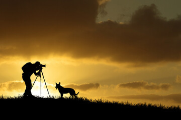 A professional photographer's silhouette is focused on shooting in a beautiful meadow.
