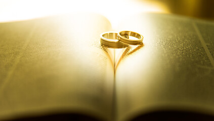 Two wedding rings with heart shadow  on a bible page