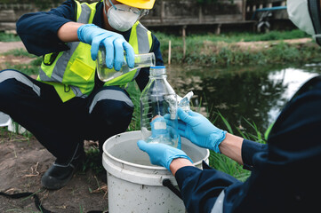 Fototapeta na wymiar Environmental Engineers Take Water Samples Into Bottles at Rotten Smelly Pond Water Sources, May Be Contaminated by Toxic Waste or Suspicious Pollution Sites.