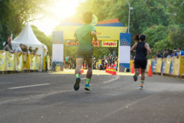 Rear view of athletes running in the race competition towards the finish line