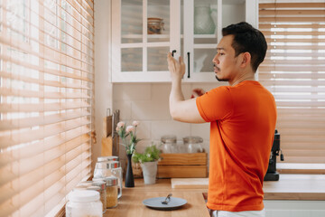 Asian man preparing his easy breakfast in the kitchen in warm light morning.