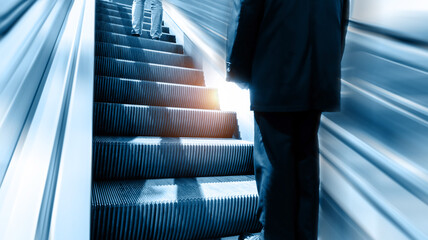 Low section of businessman standing at modern escalator - Powered by Adobe