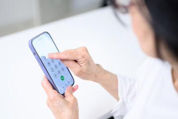 スマホで電話をかけようとする高齢者　顔無しの手元のアップ