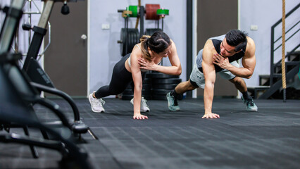 Obraz na płótnie Canvas Millennial Asian strong young male and female muscular fitness model athlete couple in sexy sport bra and legging planking bodyweight workout on floor exercise training ready to pushing up in gym