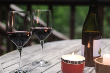 Two glasses with red wine standing on the wooden table with burning candle