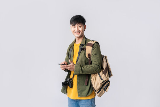 Portrait Young Asian Man Backpacker Happy Smile In Formal Shirt Using Smartphone Trading Or Chatting Or Online Shopping On Isolated Studio White Background. Asian Man Traveller In Studio Shot.