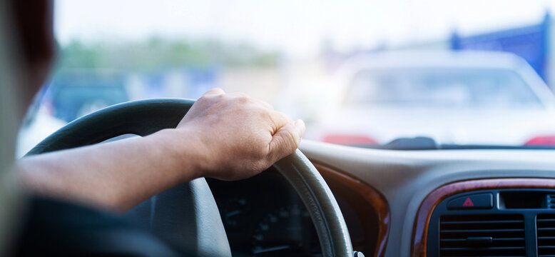 Man hand on steering wheel inside of a car at traffic jam