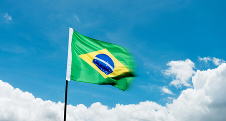 Brazilian flag waving against blue sky background