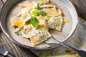 Ravioli with ricotta cheese, parmesan and spinach. Garnished with basil leaves and olive oil. Fresh and tasty classic Italian pasta dish.
