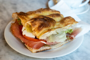 Delicious Italian focaccia bread with cold cuts, cheese and salad served with coffee in restaurant