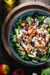 Salad with chicken, cheese, tomato and arugula. Healthy meal from superfood, rich with vitamins and minerals. Placed on wooden board.