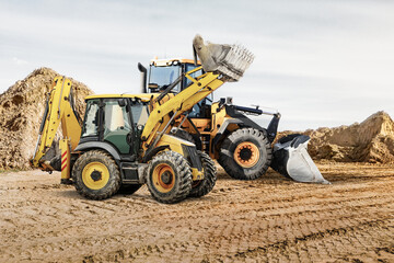 Obraz premium Modern construction machinery at a construction site in a quarry. Powerful modern equipment for earthworks. Rental of construction equipment. Excavator, dump truck, bulldozer, loader.