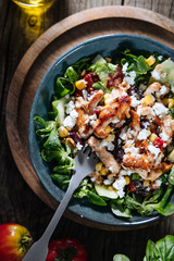Salad with chicken, cheese, tomato and arugula. Healthy meal from superfood, rich with vitamins and minerals. Placed on wooden board.