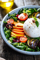 Salad with burrata cheese, peaches, tomato, plum, cherries and arugula. Italian healthy meal with lot of vitamins. Super food.
