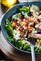 Salad with chicken, cheese, tomato and arugula. Healthy meal from superfood, rich with vitamins and minerals. Placed on wooden board.