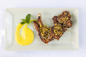 Overhead view of delicious Italian grilled lamb chop with pistachios topping and sauces