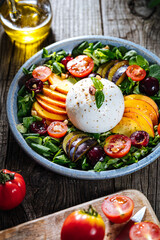 Salad with burrata cheese, peaches, tomato, plum, cherries and arugula. Italian healthy meal with lot of vitamins. Super food.