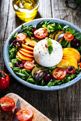 Salad with burrata cheese, peaches, tomato, plum, cherries and arugula. Italian healthy meal with lot of vitamins. Super food.