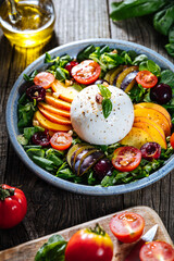 Salad with burrata cheese, peaches, tomato, plum, cherries and arugula. Italian healthy meal with lot of vitamins. Super food.