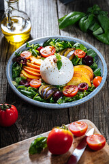Salad with burrata cheese, peaches, tomato, plum, cherries and arugula. Italian healthy meal with lot of vitamins. Super food.